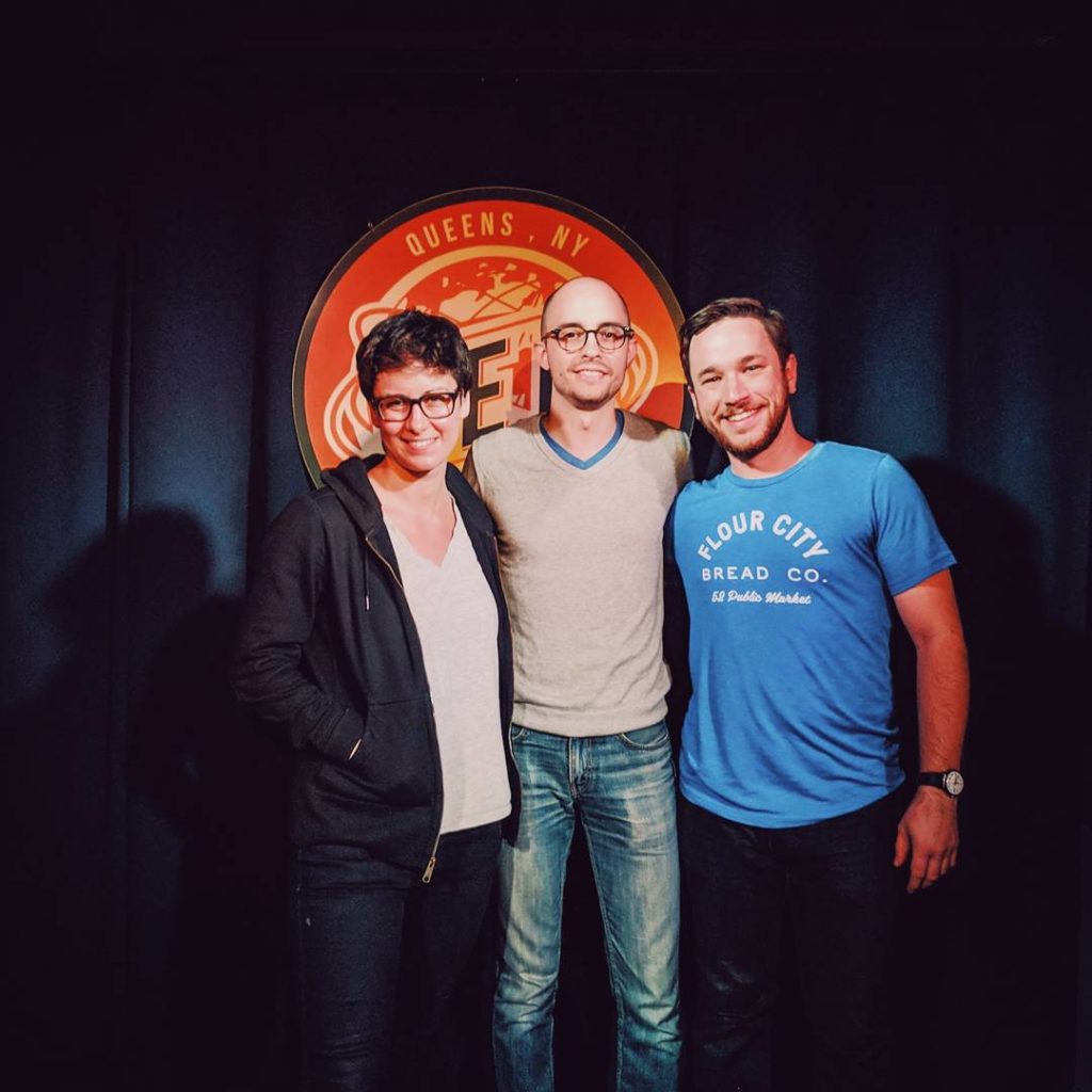 Sarah Pappalardo, Evan Barden, and Patrick Cartelli standing on a stage in front of the QED sign.