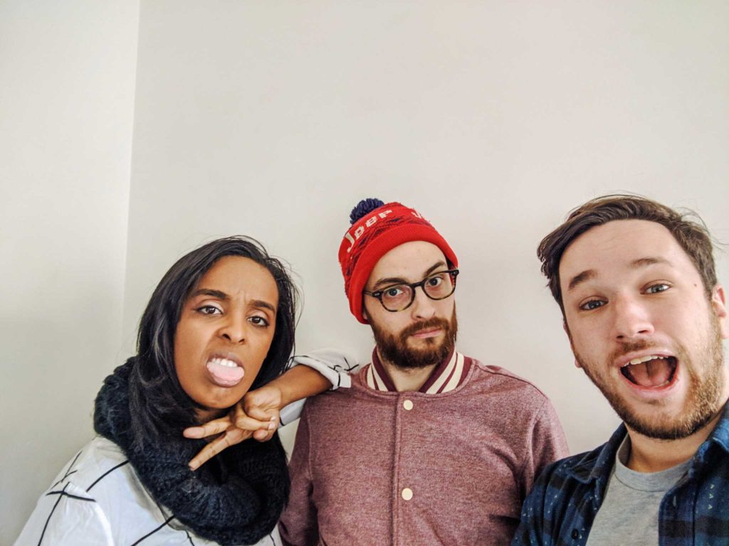 Corin Wells, giving a peace sign and sticking her tongue out, next to Evan Barden and Pat Cartelli, mouth agape